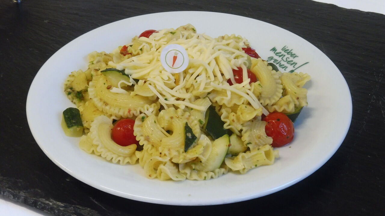 Hausgemachte Pasta (A, A1, C) mit Zucchini und Tomaten, dazu geriebener Gouda (G)